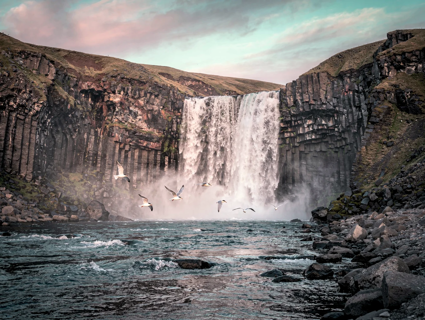 Cascading waterfall over dark basalt cliffs in Iceland